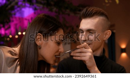 Beautiful man and woman eating sweet cake at the restaurant on a date. Stock footage. Boyfriend gives a spoon to his girlfriend to feel the taste.