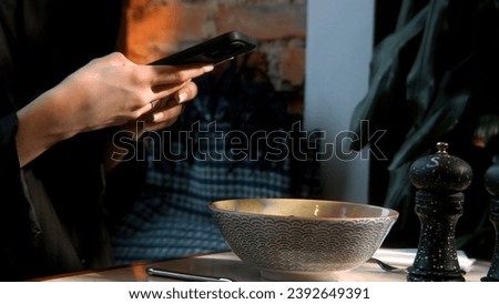 Side view of woman hands making photo of a dish in plate on mobile phone while sitting in comfortable restaurant. Stock footage. Female taking pictures with cell phone camera of delicious dish.