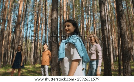 Friends play volleyball in woods. Stock footage. Group of people play ball standing in circle in forest on summer day. Friends relax in nature in sunny weather
