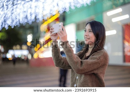 Woman use mobile phone to take photo in city at night