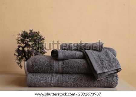 2 gray bath towels, 1 hand towel, and 2 washcloths, arranged with 1 open washcloth in front, isolated with a flower pot Royalty-Free Stock Photo #2392693987