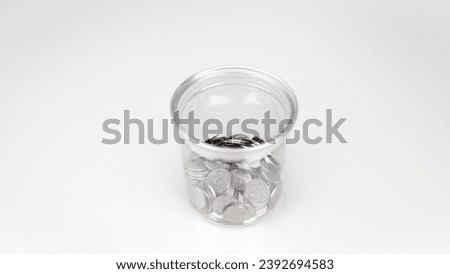 Money in a clear glass, 1 baht coin included in a container, clearly visible from the outside. white background Suitable for use in designing public relations media. Or you can use it to write.