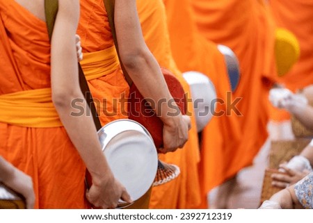 Buddhist alms giving ceremony in the early morning.Monks walk to collect alms and offerings.Sticky rice morning alms giving is held every day in Luang Prabang.Traditional ritual of alms giving in Laos Royalty-Free Stock Photo #2392712319