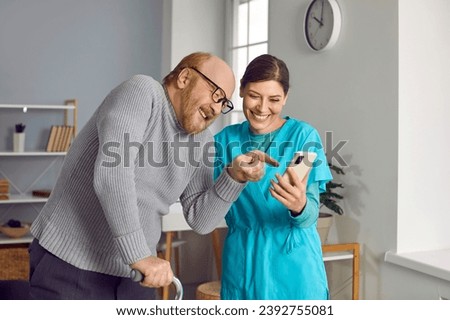 Nurse helping senior man with cane to use smartphone. Retired person and friendly caregiver looking at screen of digital device at home. Social worker caring of elderly man