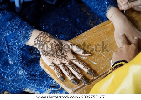 Artist applying henna tattoo on bride hands. This is a cultural custom that exists in Aceh - Indonesia. which is done to decorate the bride when getting married Caleed Boh Gaca
