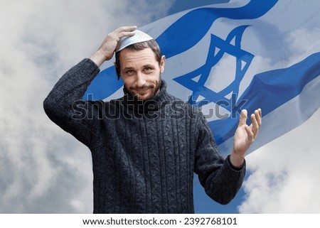 Religious jew man with smile face, holding a kippah, hand to his head against the background of the Israeli flag, beautiful sky. Handsome smiling bearded Jewish holding yarmulke for wind over his head Royalty-Free Stock Photo #2392768101