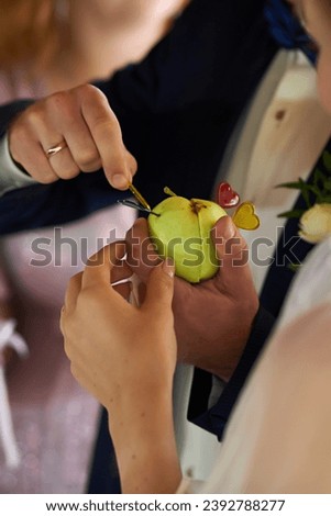 Vertical photo of the newlyweds holding a green apple at the wedding ceremony
