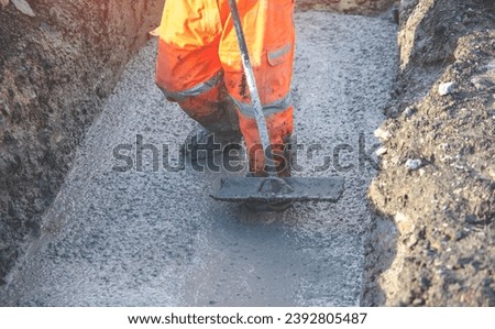 Concrete cast-in-place work. Builder leveling wet concrete. Concrete works on building construction site Royalty-Free Stock Photo #2392805487