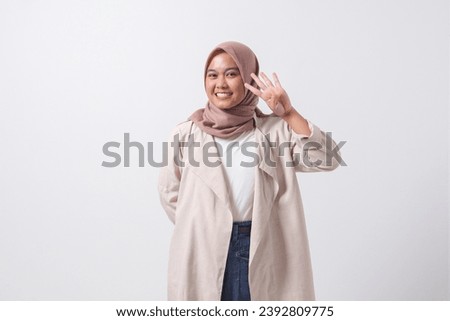Portrait of excited Asian hijab woman in casual suit showing and pointing up with fingers number four while smiling confident and happy. Businesswoman concept. Isolated image on white background