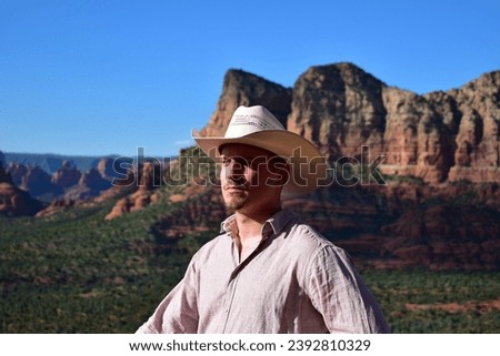 Man in pink shirt and wearing a white cowboy hat with the Sedona landscape in the Arizona desert as background