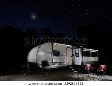 Christmas star shining brightly over an RV at a campsite surrounded by trees.