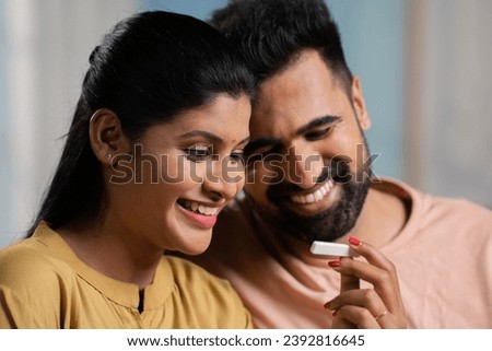 Indian couple got excited after seeing positive pregnancy test result at home - concept of expecting baby, good news and affection Royalty-Free Stock Photo #2392816645
