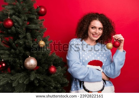 Photo of dreamy adorable lady wear ugly new year pullover holding baubles decorating x-mas tree isolated red color background