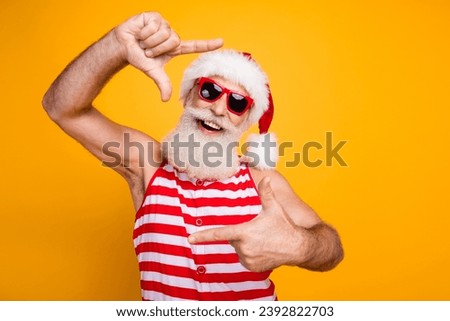 Photo of positive funny elderly guy wear new year swimsuit hat sunglass showing photo gesture empty space isolated yellow color background