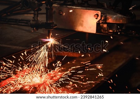 Worker cutting steel plate with acetylene welding cutting torch and bright sparks in steel industry. Royalty-Free Stock Photo #2392841265