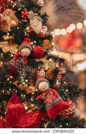 Soft toys snowman figurines hanging on a Christmas tree with golden garland lights.