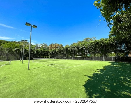 Photography of an outdoor tennis court with artificial grass surface
