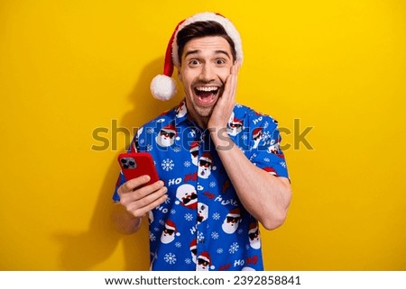 Photo of young guy wear new festive blue shirt hand cheek surprised snowing weather forecast smartphone isolated on yellow color background