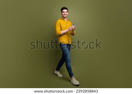 Full length photo of attractive man wear stylish clothes walking street using gps navigation google map isolated on khaki color background