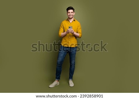 Full length photo of nice positive man popular blogger wear stylish clothes hold iphone samsung device isolated on khaki color background