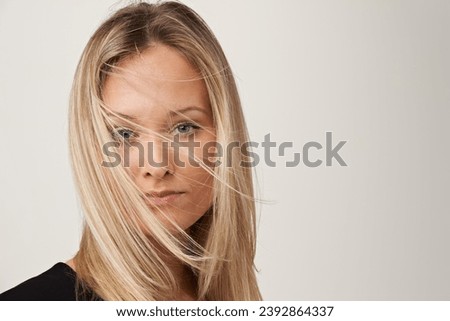Hair care, beauty and face portrait of a woman on a white background with shampoo, salon treatment and wind. Headshot of female model in studio with cosmetics, hairstyle and serious facial expression Royalty-Free Stock Photo #2392864337