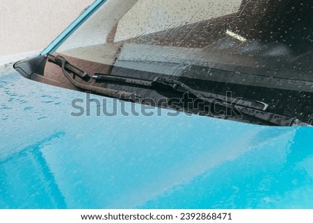 Raindrops on the car. Car element with raindrops close-up. The hood, mirror and glass of a blue car covered in raindrops. Big raindrops on the car very close Royalty-Free Stock Photo #2392868471