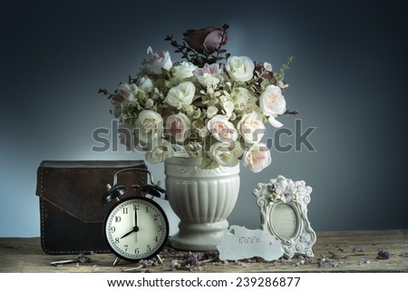 Still life with retro clock and flowers, flake, and love letter on wooden table