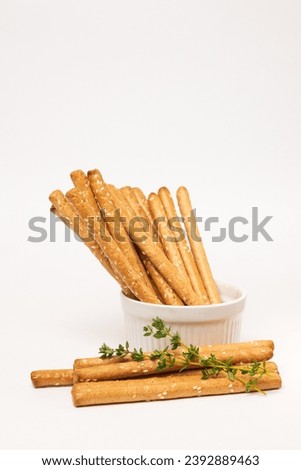 Classic crispy bread sticks grissini with thyme stems and sesame seeds in white form. Traditional Italian pastry breadsticks on white background with copy space Royalty-Free Stock Photo #2392889463