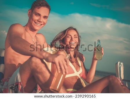 Young couple relaxing on a deck chairs on a beach 