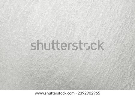Close-up of a white concrete wall with a rough texture. The wall is made up of small aggregate particles, such as sand and gravel, which are bound together by cement