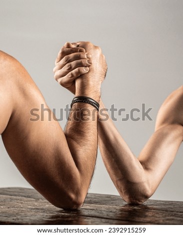 Arms wrestling thin hand, big strong arm in studio. Two man's hands clasped arm wrestling, strong and weak, unequal match.
