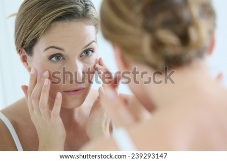 Middle-aged woman applying anti-aging cream Royalty-Free Stock Photo #239293147
