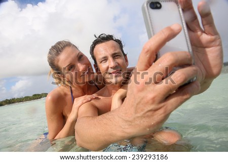Couple making selfie in the sea with waterproof smartphone