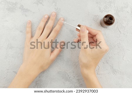 Woman applying medicine to damaged nails. Fingernails with onycholysis after removing gel polish Royalty-Free Stock Photo #2392937003