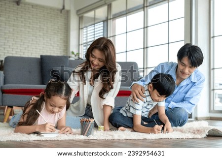 Parents encourage and have fun with their children practicing drawing on the living room floor. Children have fun drawing Family happiness in the living room