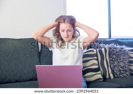 Caucasian woman sitting on the sofa and using a computer (stress and shock)