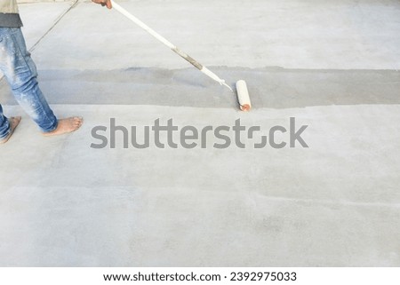 Worker and renovation work. To using roller painting mortar cement or finishing material for repair crack, skim coat or improvement surface of concrete pavement floor or slab for driveway or garage. Royalty-Free Stock Photo #2392975033