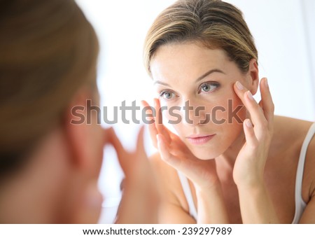 Middle-aged woman applying anti-aging cream Royalty-Free Stock Photo #239297989