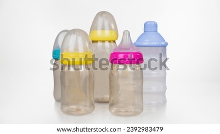 A picture of 5 baby bottles with 4 different colored caps - yellow, blue, green and pink - arranged side by side, 2 in front and 3 in the back.