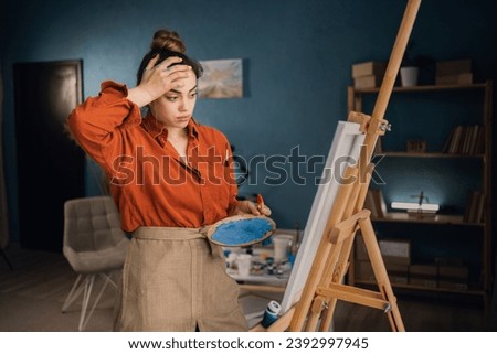 Young woman artist stressed while drawing on canvas at art studio. Copy space