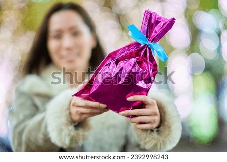 A woman holding a colorfully wrapped present