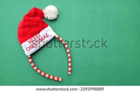Beautiful headband 
 Decorative red Santa Hat isolate on a green backdrop.
concept of joyful Christmas party,New year is coming soon, festive season decoration with Christmas elements
