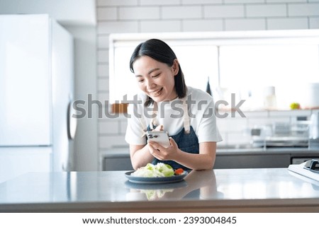 A young Japanese woman taking pictures of her cooking with a smartphone