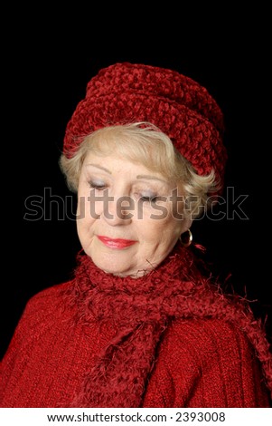 A beautiful senior lady in red smiling as she remembers.  Isolated on black.