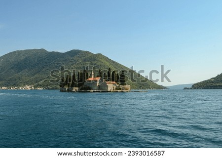Fjord in Adriatic Sea. Our Lady of the Rock island and Church in Perast on shore of Boka Kotor bay (Boka Kotorska), Montenegro, Europe. Kotor Bay is a UNESCO World Heritage Site Royalty-Free Stock Photo #2393016587