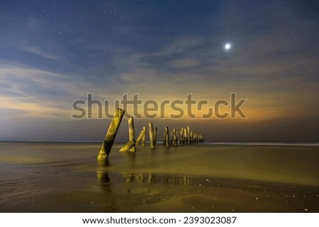Scenery view of the concrete columns of the old port with Beautiful stars night on Sao Iang Beach at Phetchaburi province. Long exposure picture 
