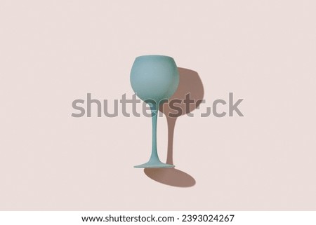 Pastel blue gray colored wine glass and sun shadow on colors background. Minimal style flat lay photo event or party concept. Aesthetic top view stylish wineglass, trend photo of summer cocktail drink