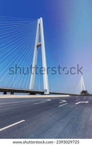 empty asphalt road and cable-stayed bridge against a blue sky, Chinese characters on the bridge tower read: Wuxue Bridge Royalty-Free Stock Photo #2393029725