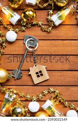 Key to house with a keychain tiny home on wooden background with Christmas decor layout. Gift for New Year, Christmas. Building, project, moving to new house, mortgage, rent and purchase real estate