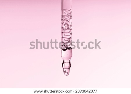 Pipette serum with clear liquid niacinamide, hyaluronic or Aha Bha acids on a pink white isolated background. Textured swatch skincare. Laboratory cosmetic Royalty-Free Stock Photo #2393042077